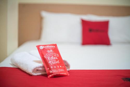 een rood pakje tandpasta bovenop een bed bij RedDoorz Syariah near Taman Siring 2 in Banua Anyar