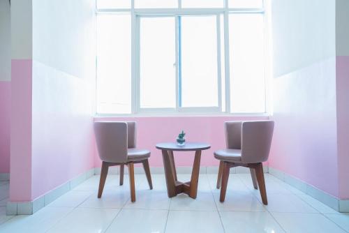 two chairs and a table in a room with a window at RedDoorz Syariah near Taman Siring 2 in Benuaanyar
