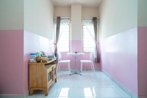 a room with pink and white walls and a table and chairs at RedDoorz Syariah near Taman Siring 2 in Benuaanyar