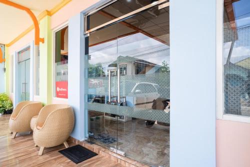 a glass door with two chairs in a room at RedDoorz Syariah near Taman Siring 2 in Benuaanyar