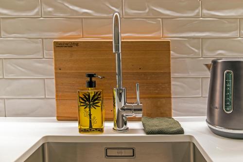 a kitchen sink with a faucet and a soap dispenser at Funk in the City - Luxury Laneway Apartment with Single Garage in Christchurch