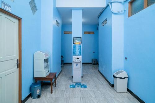 RedDoorz Syariah near Taman Siring 2 في بينوانيار: غرفة زرقاء مع جهاز في الغرفة