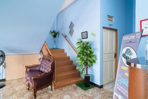a room with a staircase with a chair and a plant at RedDoorz Syariah near Taman Siring 2 in Benuaanyar