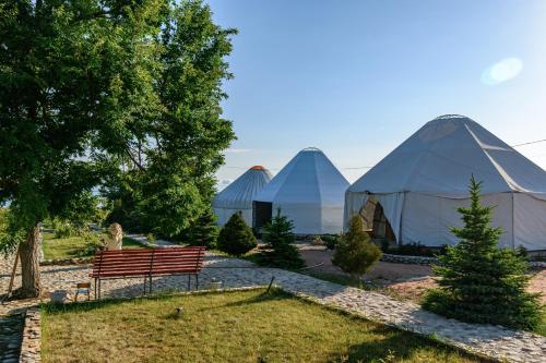 a park with three domes and a bench and trees at Yurt camp Meiman Ordo in Bokonbayevo