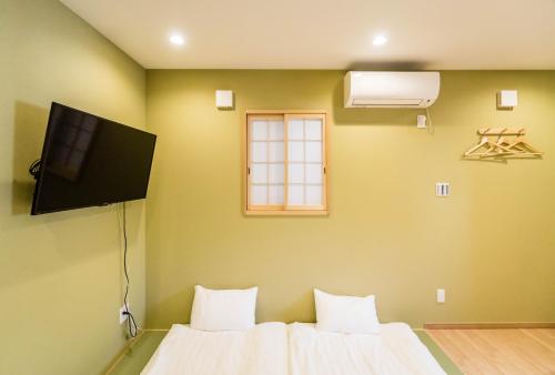 a room with a bed with a tv on the wall at HANASTAY花渓居 · 丘（OKA) in Osaka