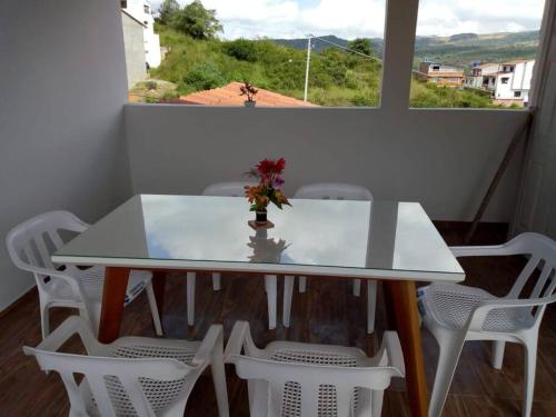 una mesa blanca con sillas blancas y un jarrón con flores. en Agradable casa para alojamiento completo CURITI, en Curití