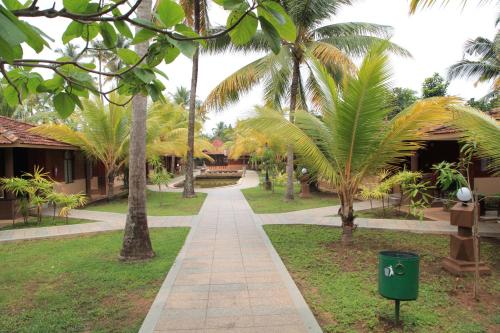 a walkway through a park with palm trees at Cherai Beach Resorts in Cherai Beach
