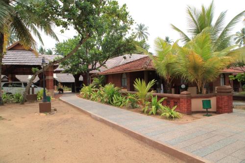 a building with palm trees and a walkway at Cherai Beach Resorts in Cherai Beach