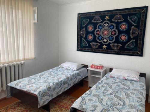 a room with two beds and a painting on the wall at Nurgul in Bokonbayevo