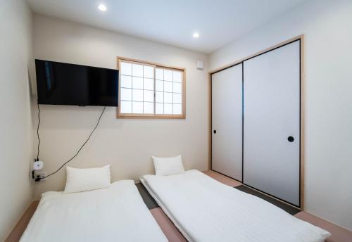 2 letti in una camera con TV a schermo piatto di HANASTAY花渓居 · 丘（OKA) ad Osaka