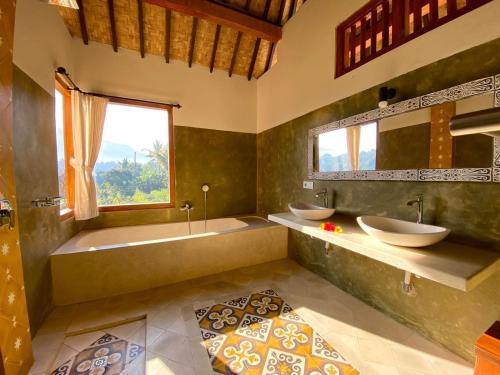 a bathroom with two sinks and a tub and a window at Kubu Tani in Sidemen