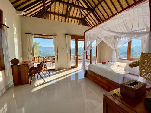 a bedroom with a bed and a desk and some windows at Kubu Tani in Sidemen