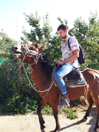 a man riding a horse with a dog on its back at Nurgul in Bokonbayevo