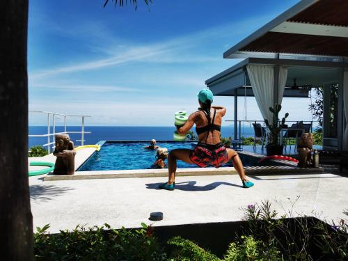 a woman sitting on a bench next to a swimming pool at VILLA TSAY - Nature, Privacy, Elegance in Haad Yao