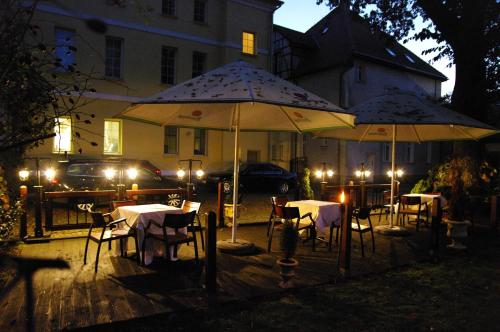 two tables and chairs with umbrellas in front of a building at Pensjonat - Restauracja Żółty Domek in Szczecinek
