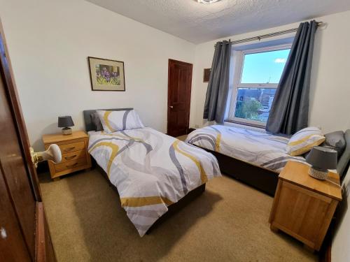 een slaapkamer met twee bedden en een raam bij 2 Mill Street in Penrith