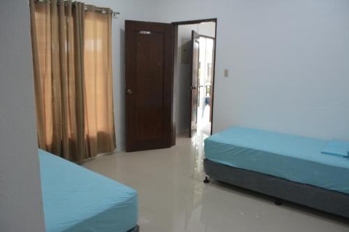 two beds in a room with a door and a mirror at Sergi's Resort and Hotel in Palompon