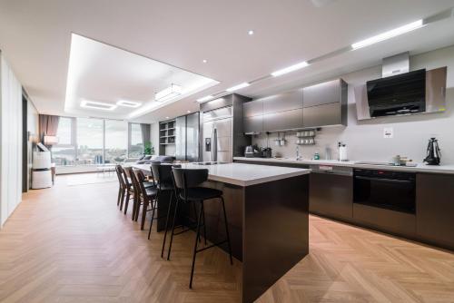 a large kitchen with a counter and chairs in it at Le Collective Busan station in Busan