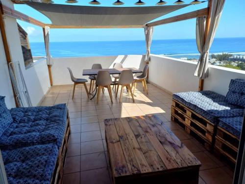 a balcony with a table and chairs and the ocean at Couleur lagon in Saint-Leu