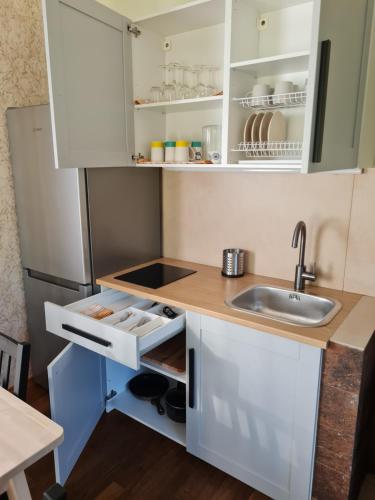 a small kitchen with white cabinets and a sink at Atostogų namelis-pirtis Prie upės in Anykščiai