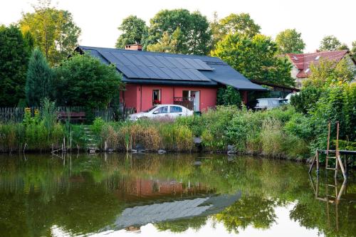 ein rotes Haus neben einem Wasserkörper in der Unterkunft Stanica pod Zadzierną Domki całoroczne in Lubawka