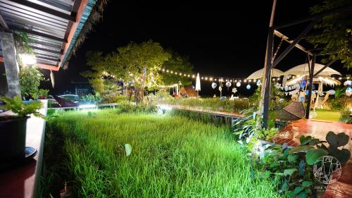 a garden with grass and lights at night at Rice Wonder Cafe & Eco Resort in Rayong