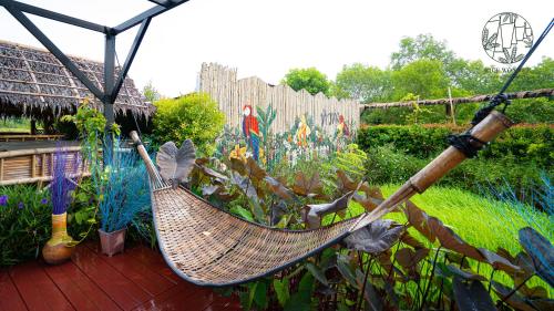 a hammock is hanging in a garden with plants at Rice Wonder Cafe & Eco Resort in Rayong