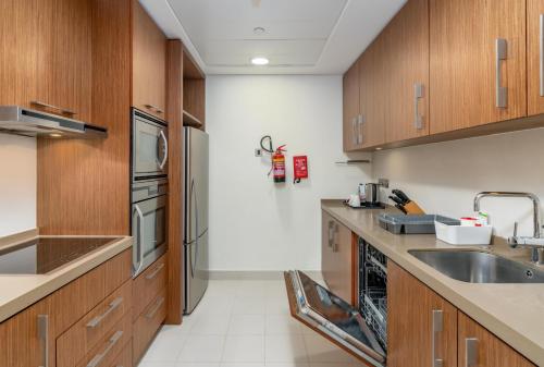 a kitchen with wooden cabinets and a sink at Adagio Abu Dhabi Al Bustan in Abu Dhabi
