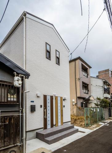 a white house with yellow doors on a street at HANASTAY花渓居 · 尺八（SYAKUHACHI) in Osaka