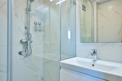 a white bathroom with a shower and a sink at Cosy Studio in the City center with Air conditioneer! in Klaipėda