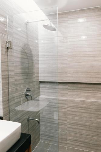 a bathroom with a glass shower with a sink at El Sancho Hotel in Naga