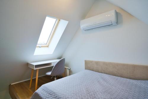 a bedroom with a bed and a desk and a window at Cosy Studio in the City center with Air conditioneer! in Klaipėda