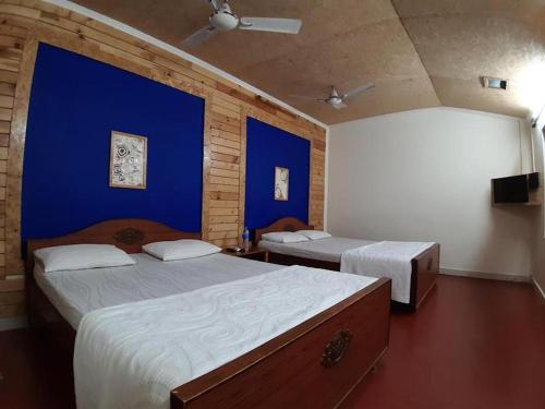 Duas camas num quarto com paredes azuis em Royal Cottage, Anaimalai multiple room em Pollachi