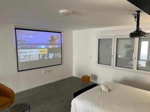 NG SuiteHome - Queven - Balnéo - Netflix - Wifi في Quéven: غرفة بسرير وشاشة عرض على الحائط