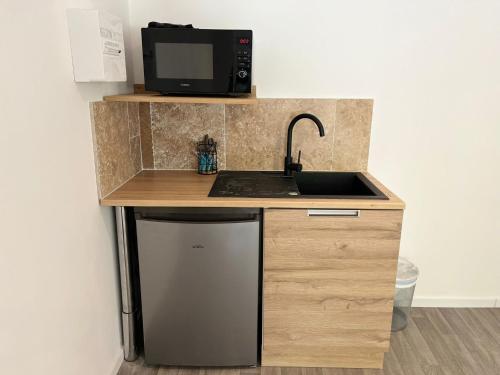 a small kitchen with a sink and a microwave at NG SuiteHome - Queven - Balnéo - Netflix - Wifi in Quéven
