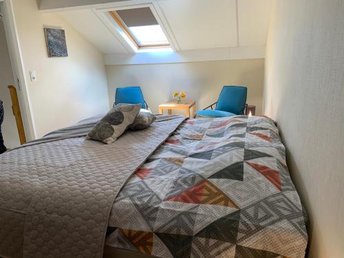 a bedroom with a bed and two blue chairs at Castorama in Rochehaut