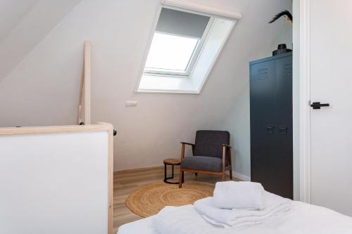 1 dormitorio con cama, ventana y silla en Paviljoenwei 10, appartement 39 Sneek - Offingawier, en Offingawier
