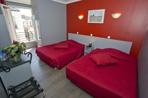 two beds in a room with red walls at Hipotel Paris Voltaire Bastille in Paris