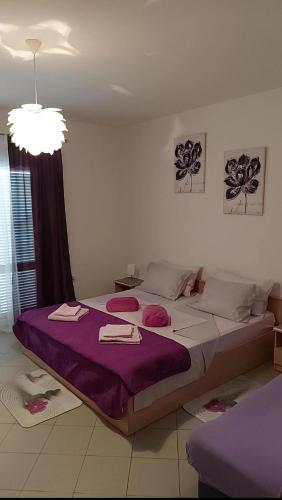 a bedroom with a large bed with purple sheets at Apartmani Katarina in Rab