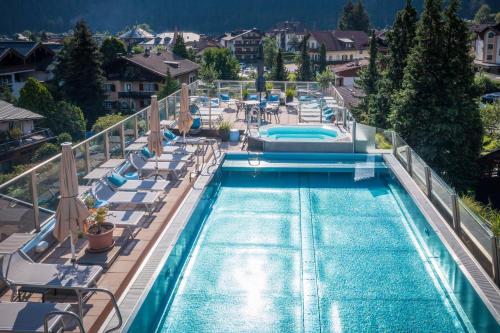邁爾霍芬的住宿－MANNI das Hotel，享有带躺椅的游泳池的顶部景致