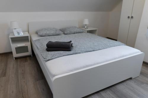 ein weißes Bett mit einer schwarzen Tasche drauf in der Unterkunft Olivér 22 Apartman in Fonyód