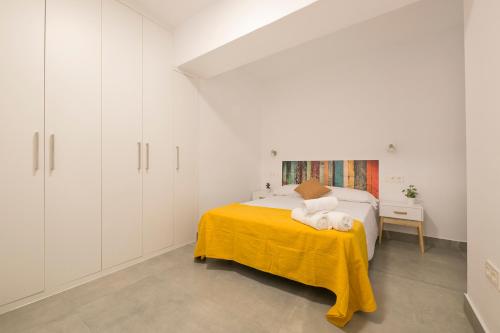 1 dormitorio blanco con 1 cama con manta amarilla en Apartamento Ribera del Genil Centro, en Granada