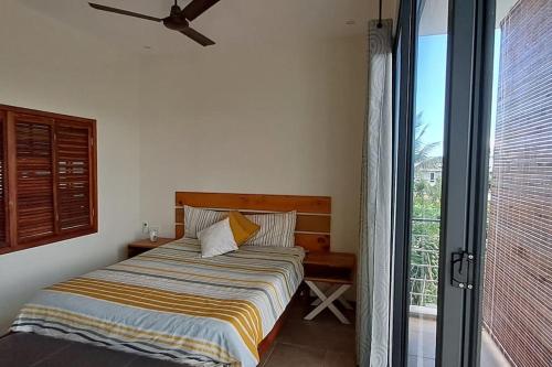 een slaapkamer met een bed en een groot raam bij Les Villas Thorel in Rivière Noire
