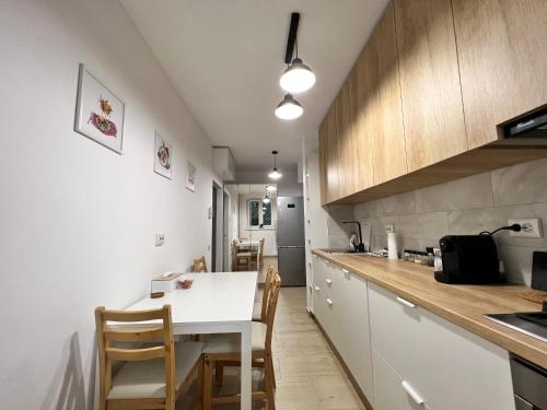 a kitchen with a white table and wooden cabinets at RSA apartment - Comfort near City Centre in Bucharest