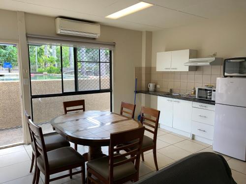 a kitchen with a table and chairs and a refrigerator at Cairns City Sheridan Motel in Cairns