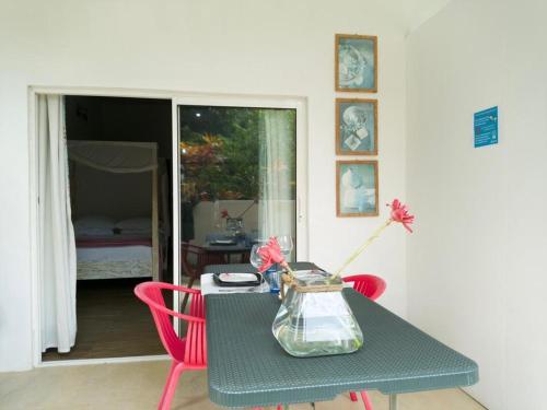 a table with two red chairs and a vase with flowers on it at Le Comfort (self catering) in Anse Royale