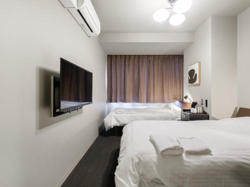 小樽市にあるTabist fami THE GREEN OTARUのベッド2台、薄型テレビが備わるホテルルームです。