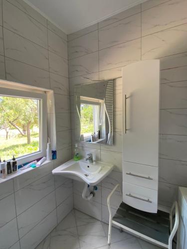 La salle de bains blanche est pourvue d'un lavabo et d'un miroir. dans l'établissement Casa Illyria, à Gusinje