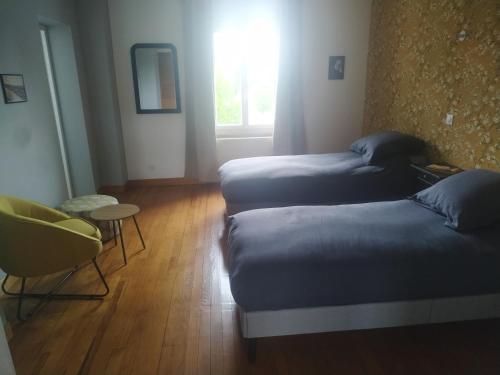 a room with two beds and a table and a window at Le Temps retrouvé in Concevreux