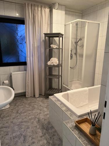 La salle de bains est pourvue d'une douche, d'un lavabo et d'une baignoire. dans l'établissement Domizil Altötting, à Altötting